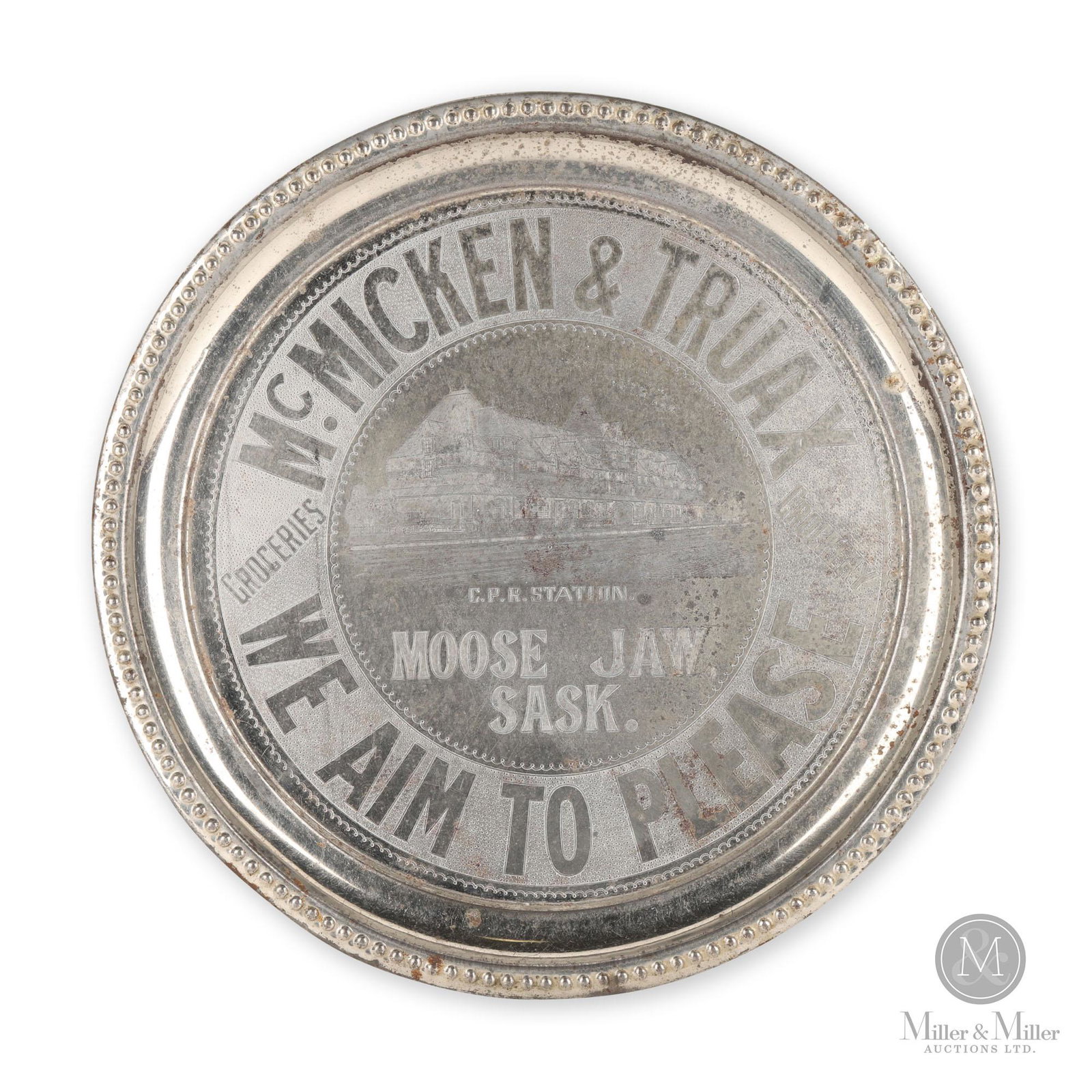 McMicken & Truax Moose Jaw, SK Grocery CPR Station Tray: Canadian. 1920s. Nickel plated copper, stamped. Features a detailed stamped image of the Canadian Pacific Railway station in Moose Jaw, Saskatchewan. Light surface oxidation, most noticeable to the ri