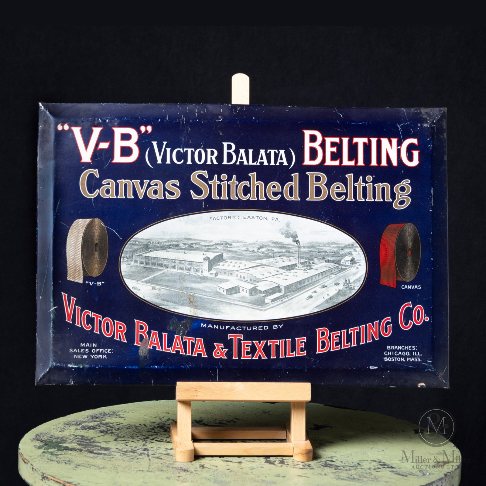 Victor Balata V.B. Belting Factory Scene Sign: American. 1910s. Single-sided tin over cardboard (TOC). Marked, on reverse edge. 13.25" x 19". Authenticated by The Authentication Company (TAC #500616). From the Norm West Collection.