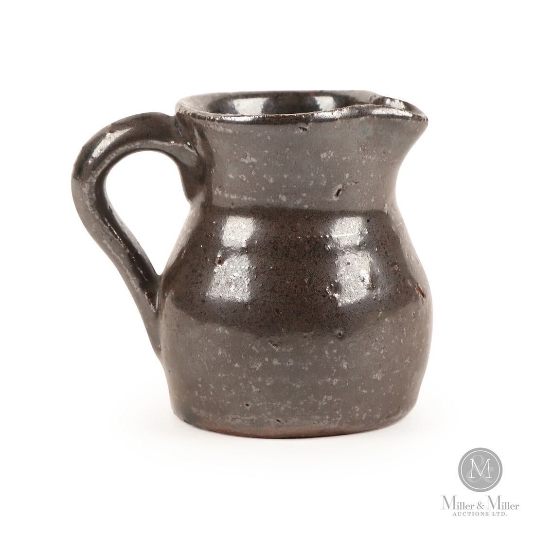 Miniature Redware Pitcher: Canadian. Ceramic. A redware miniature jug in dark brown slip glaze. Very good condition with rim wear and a minor nibble on the spout. Ontario, late 19th century. 3" x 3.25" x 2.5". From the Sherry B