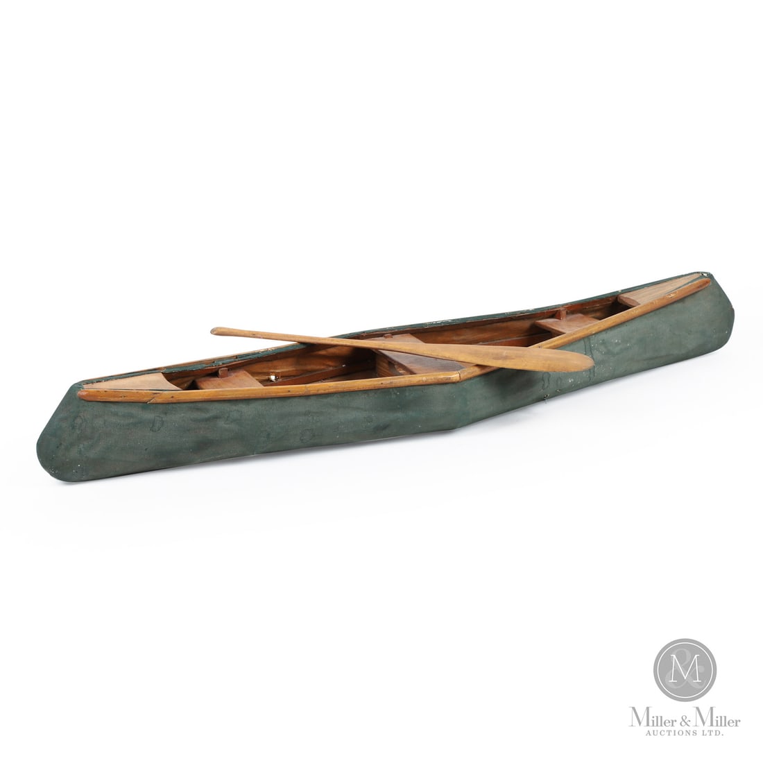 Canvas Model Canoe: Quebec, Canada. c. 1925. Wood/Canvas. A handmade canvas covered miniature canoe in original green paint and with the original paddle. The gunwales are made in two pieces joined at mid-point.