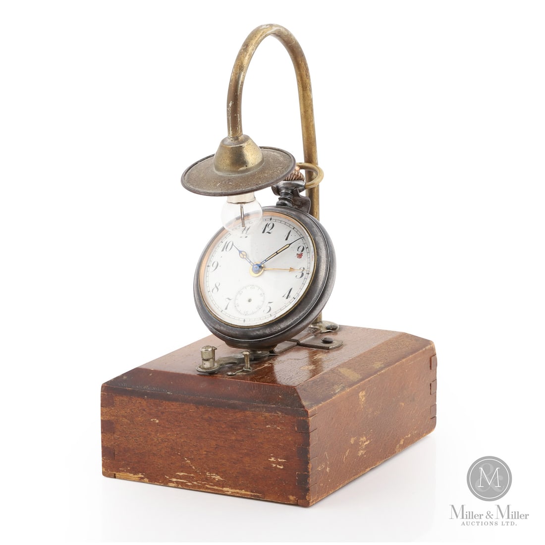 Night Light Pocket Watch Stand: German. Wood with nickel-plated apparatus. This Night Light Watch Stand is a practical horological accessory designed for the bedside table of a mid-century collector. Crafted from wood, the stand fea