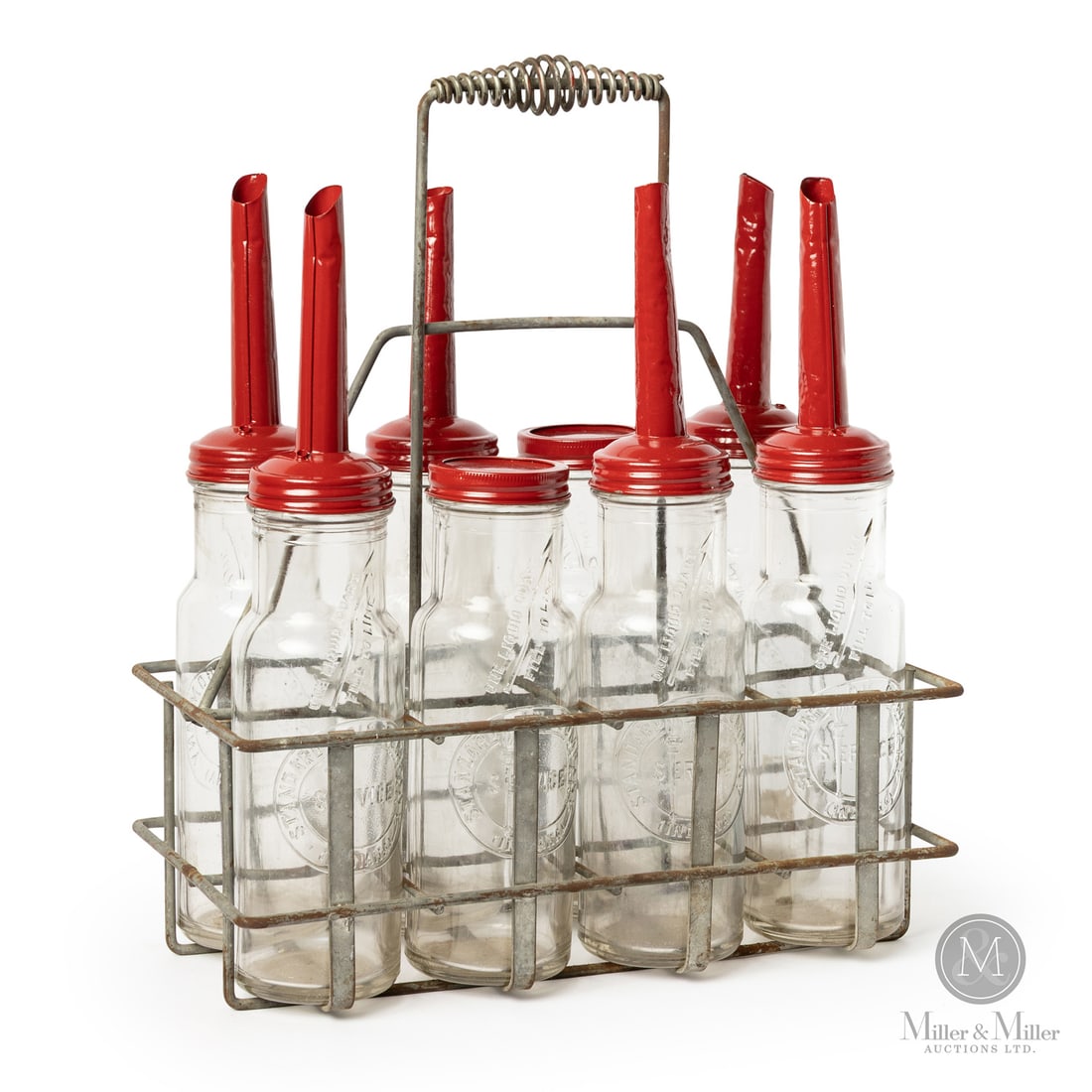Standard Oil Quart Bottles in 8-Bottle Wire Carrier: 1920s-1930s. Embossed glass. Glass oil bottles were commonly used from 1910 to 1934, and again during wartime metal shortages. Two bottles with minor lip chips. One bottle retains a partial paper