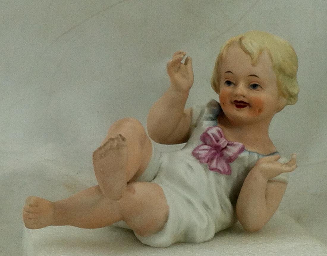 Bisque Girl Piano Baby: Cherubic hand painted piano baby girl measures 5" l. x 4" h. Marked in red on the bottom: "23/80. No condition issues of any kind.