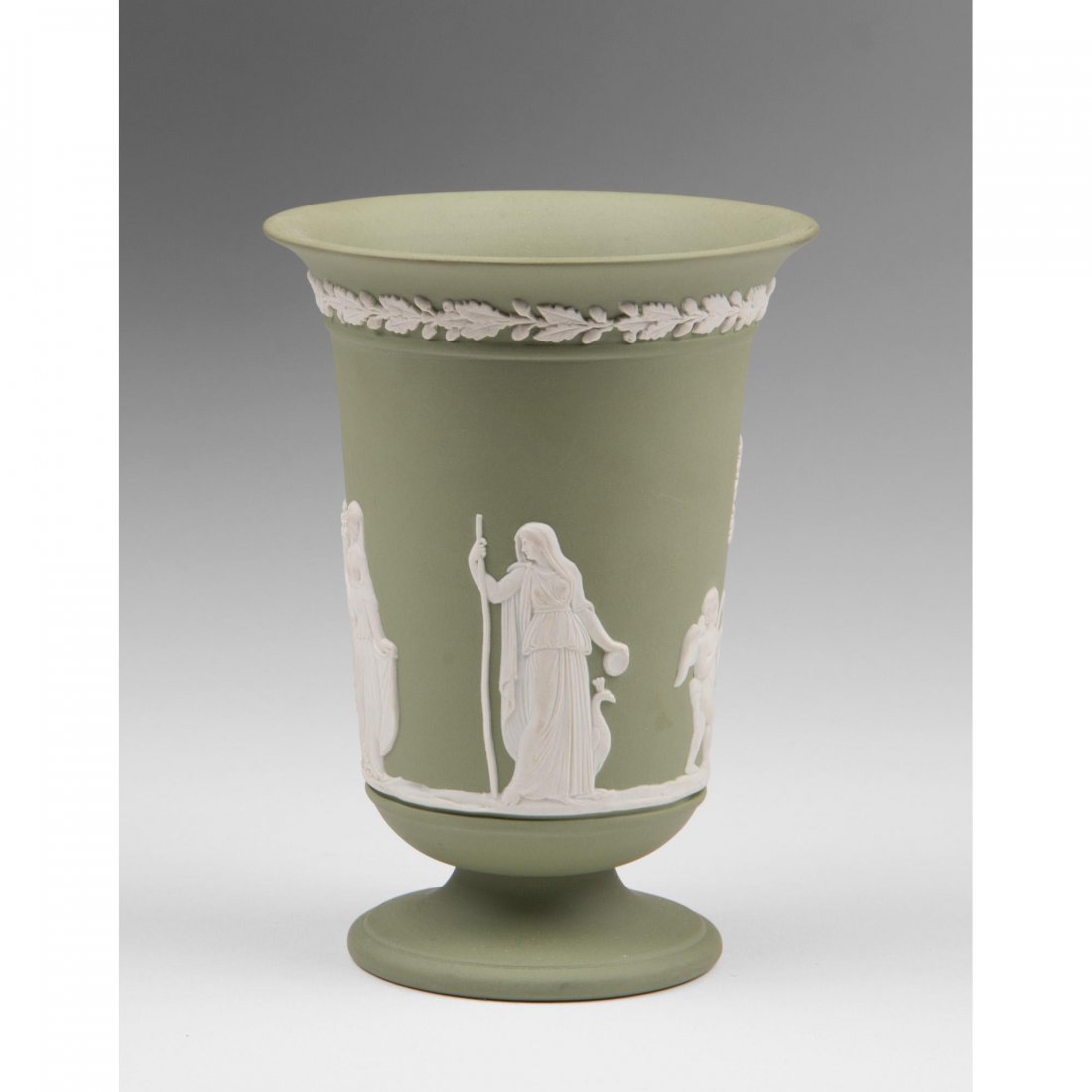 Green Jasperware Wedgwood Vase: A green Jasperware Wedgwood vase decorated with a Neoclassical processional. The vase is cone shaped with a flared lip raised on a socle.Size: 5 ½” Height.