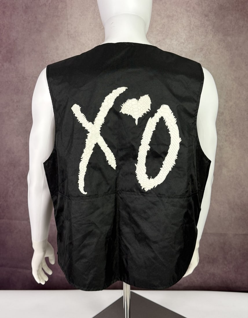 The Weeknd's Wardrobe - XO vest: The Weeknd XO black Vest with Python Skin Logo The Weeknd Exclusive. XO is The Weeknd's own label and lifestyle imprint, released through Republic Records. CONDITION: Pre-owned. The photographs are pa