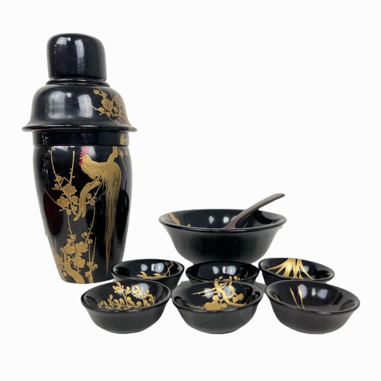 Lot of 12 Japanese Lacquered Gold Painted Items: A lot of 12 vintage Japanese lacquered items to include a black lacquer martini shaker, bowl and saki cups. Red lacquer tray that appears older. A brown lacquer spoon. Also includes a silver painted b