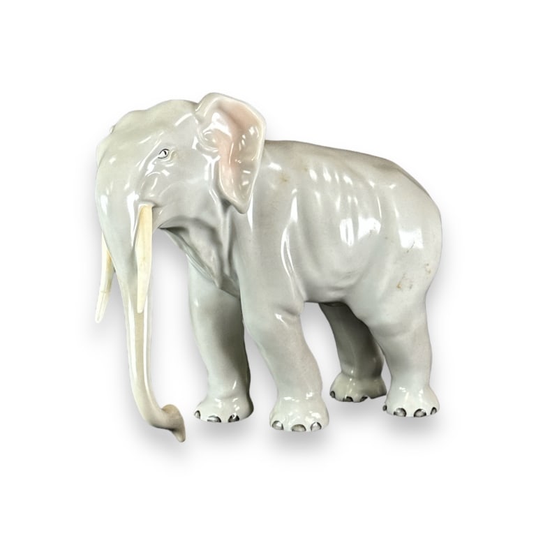 Herend Hungarian hand painted porcelain sculpture depicting a standing elephant. Bottom with blue: Herend Hungarian hand painted porcelain sculpture depicting a standing elephant. Bottom with blue stamp mark. Measures approx. 6" height x 7 1/4" width x 3 3/4" depth. Tip of one tusk has been glued b