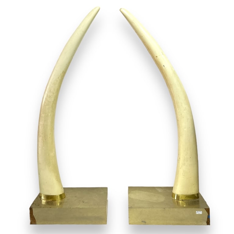 A pair of Hollywood Regency large faux elephant tusks mounted to metal veneer bases. Appears to be (1 of 3)