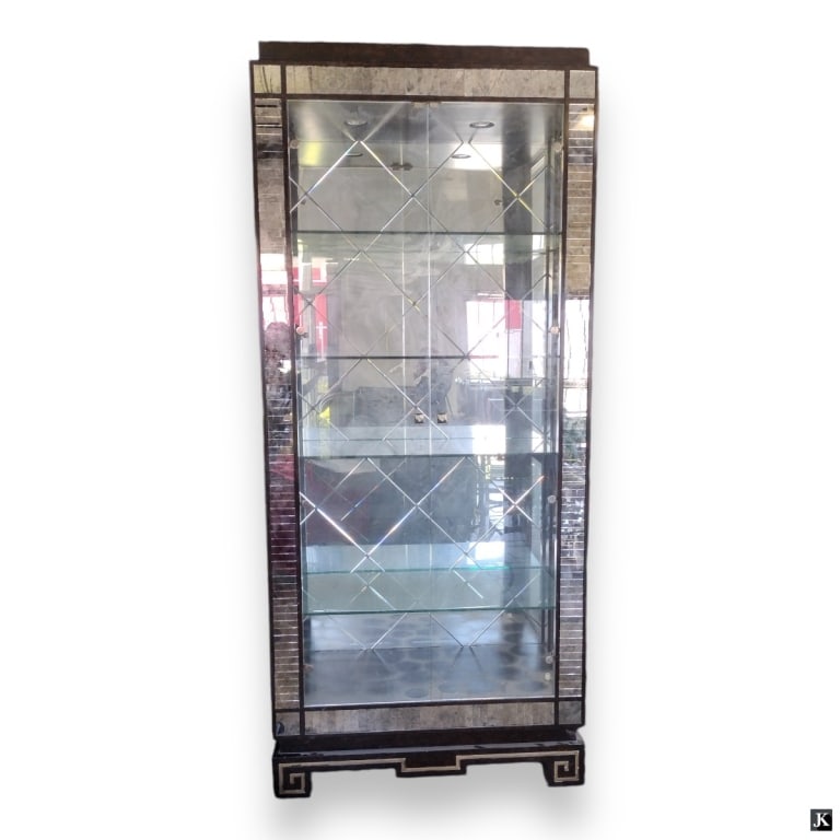 Wooden Mirror Veneer Greek Key Curio Cabinet: A wooden curio cabinet crafted of wood featuring a glass mirror panel veneer design. Has double door glass front. Beveled glass side panels. Completed with a Greek Key Meander design to base. Cabinet 