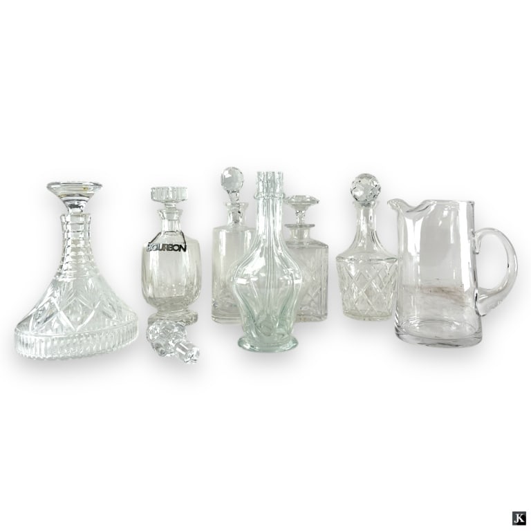 7 Glass Decanters & 1 Pitcher: 7 Glass Decanters,1 Pitcher, 1 stopper. The pitcher measures 9" H. Unmarked. Good used condition, 1 decanter with noticeable cloudiness or in overall good used condition. LA/B13/SH:20B