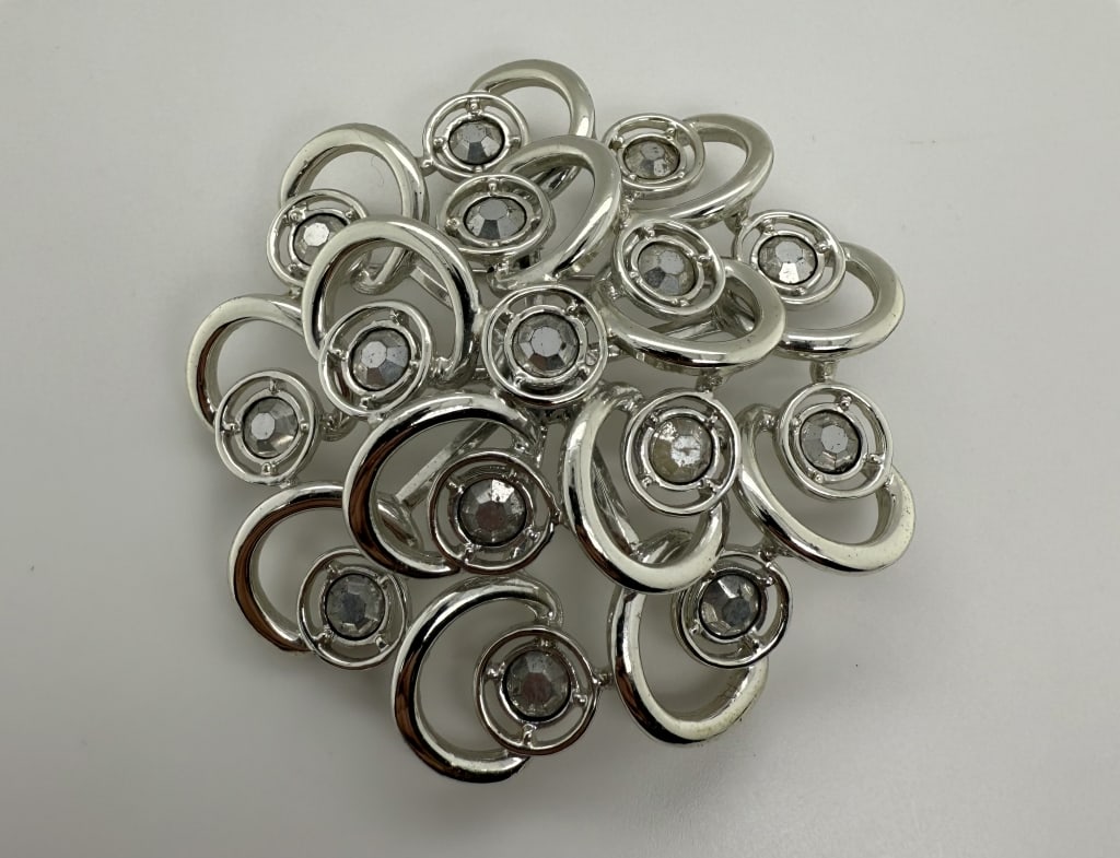 Vintage Sarah Coventry Gemstone Swirl Brooch: Vintage Sarah Coventry gemstone decorated swirl brooch. Stamped 'c. SARAHCOV' verso. Some signs of wear/use, otherwise in very good condition.