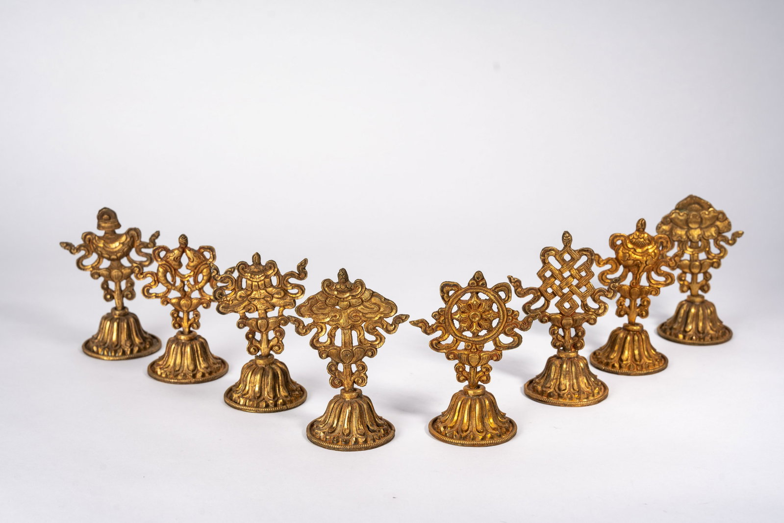 Group of Eight Tibetan Sacred Gilt Copper Ashtamangala: Group of Eight Tibetan Sacred Gilt Copper Ashtamangala Group of Eight Tibetan Sacred Gilt Copper Ashtamangala, Qing Dynasty, each supporting an auspicious buddhist attribute forming group of eight Ash