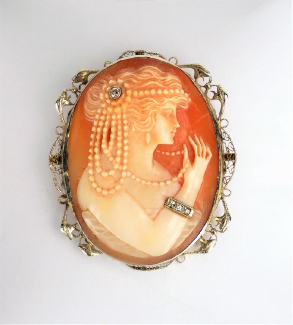 14K YELLOW GOLD AND DIAMOND HABILLE CAMEO: 14K YELLOW GOLD AND DIAMOND HABILLE CAMEO – Intricate white gold setting with finely carved shell cameo, woman has several strands of beads in her hair and around her neck, bracelet and hair pin ado