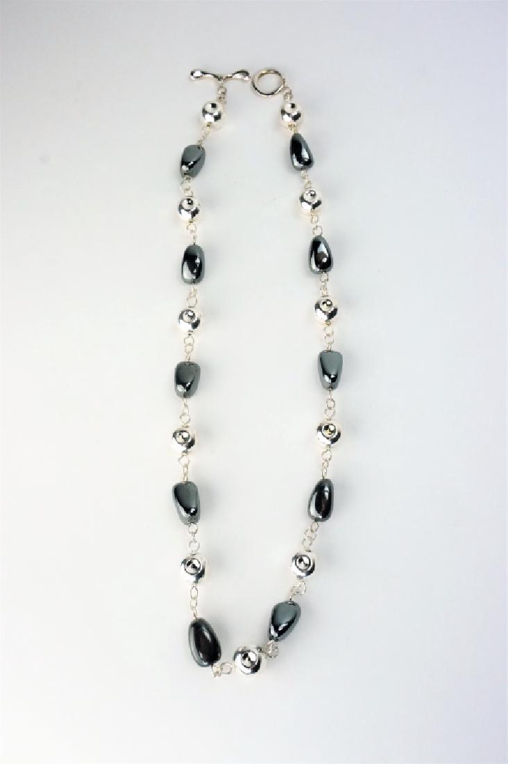 RLM STUDIO STERLING & HEMATITE NECKLACE: RLM STUDIO STERLING & HEMATITE NECKLACE – This 25” Robert Lee Morris necklace alternates between hematite beads and pierced sterling bead; toggle clasp, marked “RLM Studio 925 China” on toggle