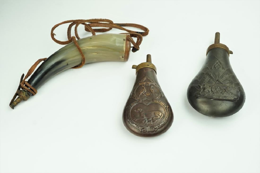 (3) ASSORTED VINTAGE POWDER HORNS / FLASKS: (3) ASSORTED VINTAGE POWDER HORNS / FLASKS Includes powder horn made of horn with brass spring loaded cover and (2) embossed copper powder flasks, one has a dog and birds, the other has a cannon and f