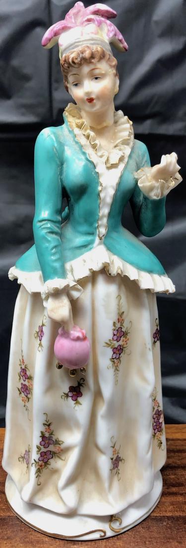 Dresden Lady Figurine Holding Pink Purse: Description: Dresden lady Figurine wearing green coat and holding pink purse. Material: porcelain. Measurement: approximate 9" H (INCHES). Shipping cost: $10