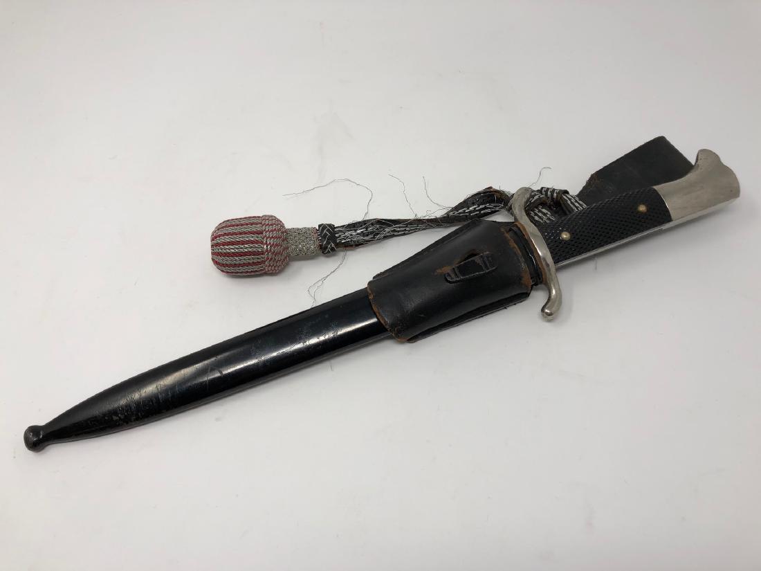 German Fireman: Description: German Fireman's dress bayonnet/dagger in black metal scabbard from WWII era. Includes leather belt holder; textured hilt. Material: metal; leather. Measurement: approximate 16"l in scabb
