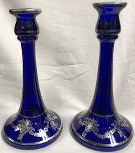 Cobalt Blue Glass Candlesticks with Silver Overlay: Description: Sublime vintage cobalt blue glass candlestick pair, artfully decorated with silver overlay at base and lip. Some wear to overlay on base on one candlestick. Material: glass. Measurement: