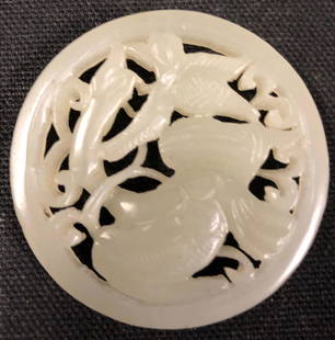 Carved Jade Amulet: Description: Highly detailed circular-shaped jade carving depicting a long necked bird entwined amid florals. Carved from the coolest, pale celadon green jade, almost white. Jade has been the most