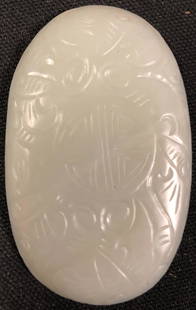 Carved Jade Amulet: Description: Highly detailed circular-shaped jade carving depicting a long necked bird entwined amid florals. Carved from light olive green-hued jade. Jade has been the most highly esteemed stone in