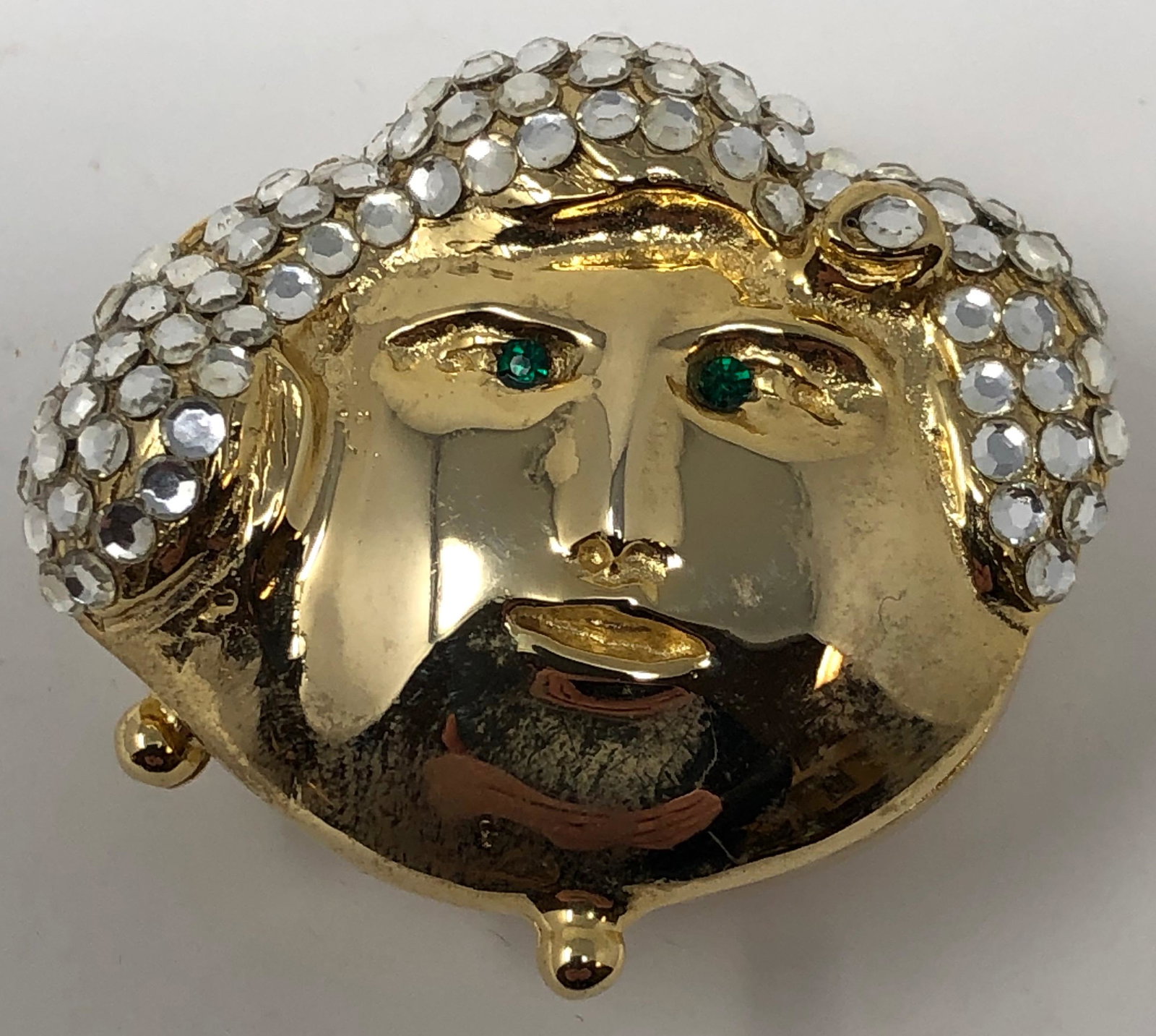 Unique Pill Box: Description: Interesting and unique pill box in the shape of a face with rhinestone hair and small, green glass eyes. Crafted in gold tone metal. A pretty addition to any pocketbook. Material: metal; 