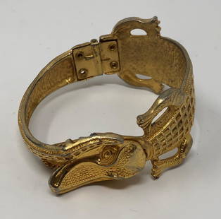 Bite Free Alligator Bypass Bracelet: Description: Fun and whimsical alligator bypass bracelet in gold tone metal. The alligator has an open jaw displaying teeth; long tail wraps up to head. Measurement: approximate ladies size 7. Materia