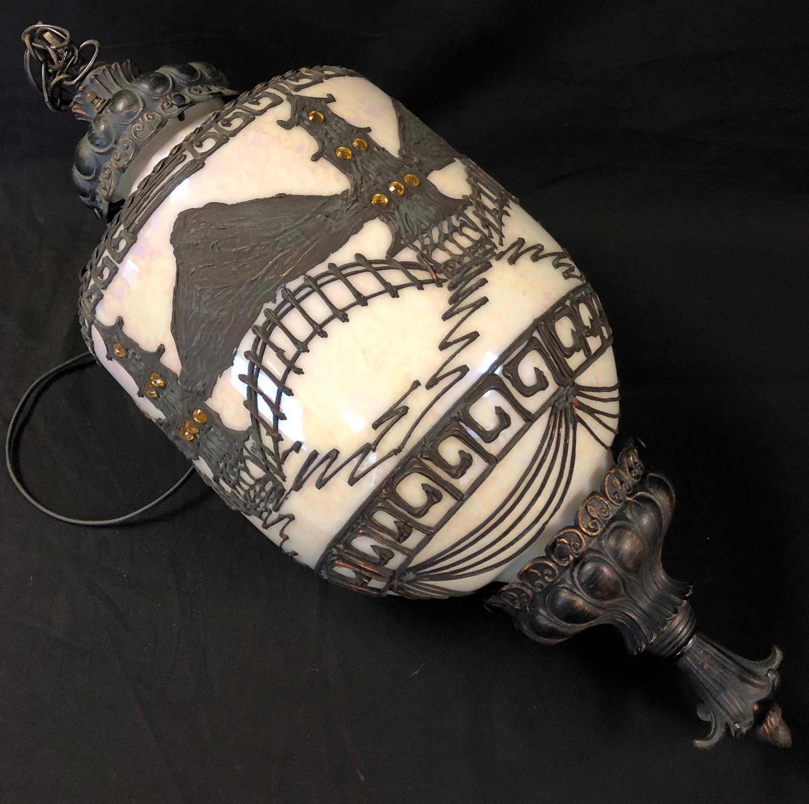 Antique Hanging Milk Glass Lamp: Description: Antique milk glass and metal hanging pendant lamp. Accented with striking Asian-inspired overlay over the milk glass globe. Equipped with hanging chain and electric cord. Material: glass;