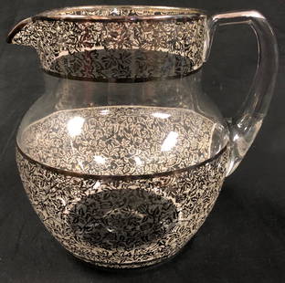 Vintage Glass Pitcher with Silver Overlay: Description: Vintage handled glass pitcher with silver overlay in a delicate leaf pattern. Lip of pitcher is lined in silver. Material: glass; silver. Measurement: approximate7.5"h (INCHES). 