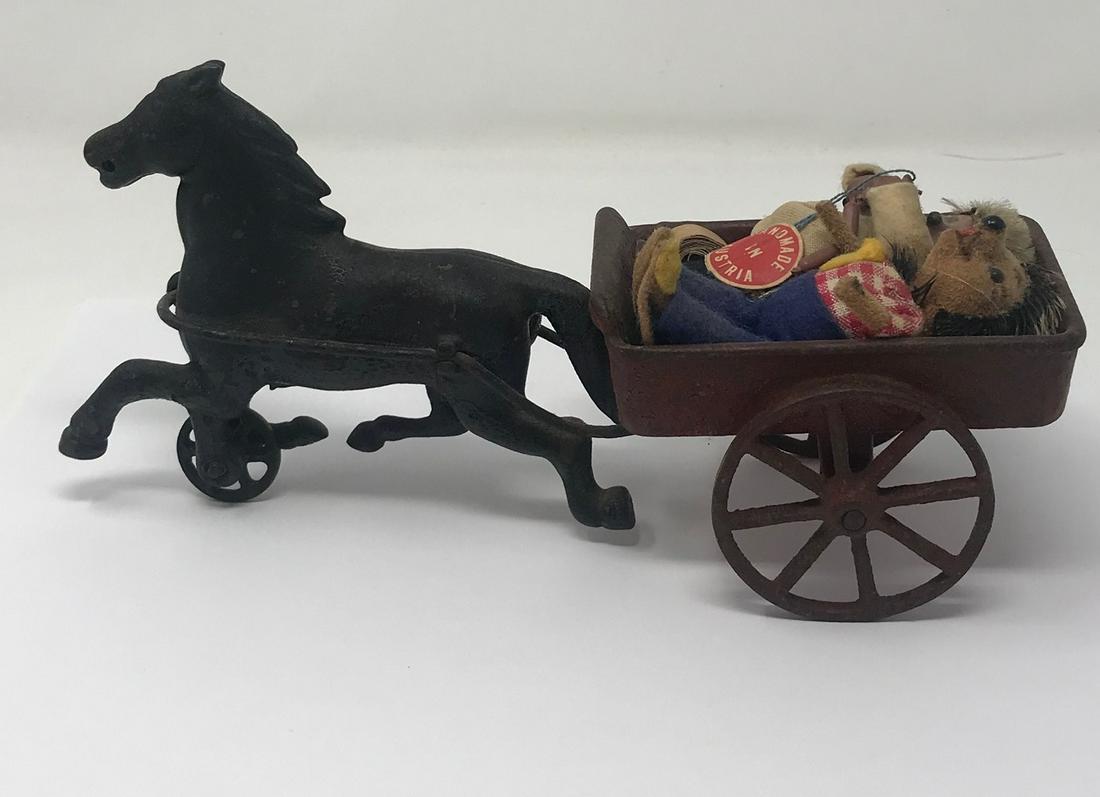 Bronze horse sculpture, with red wagon and dolls: Description: Bronze horse sculpture pulling red metal wagon two dolls dressed in farm clothes fabric round label MADE IN AUSTRIA 9" len x 4.5" high, wagon has two large working wheels, one working bro