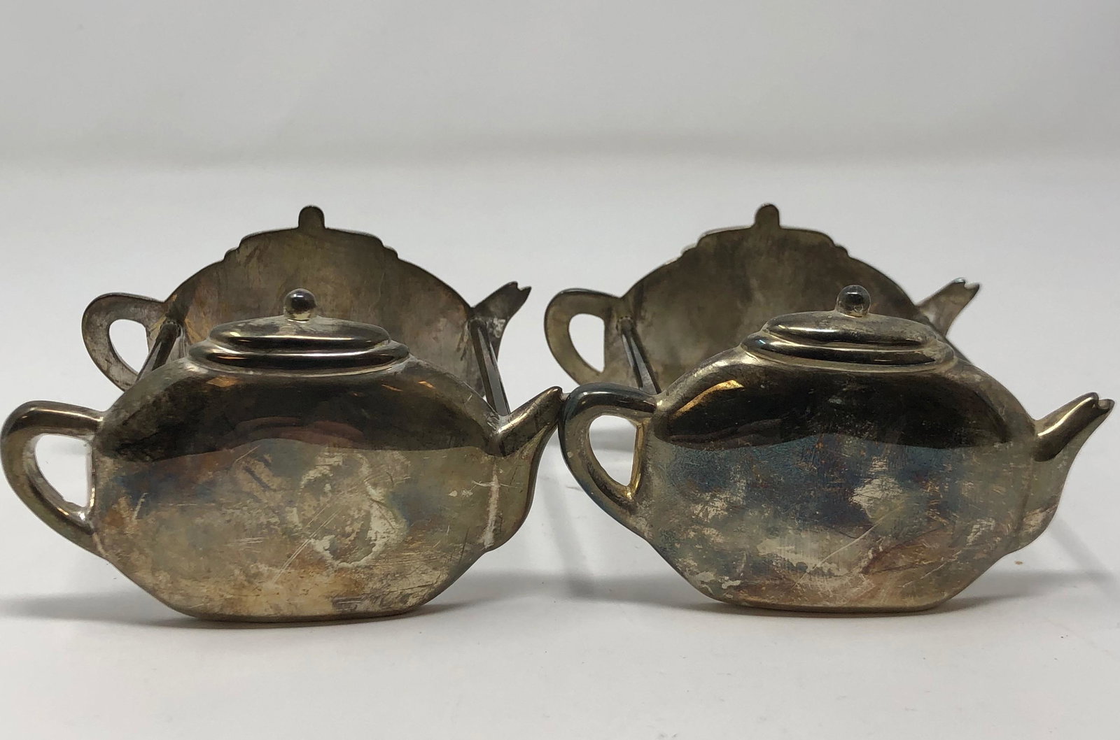 Vintage Pair of Silver Metal Tea Bag Holders: Description: Handy and eye catching pair of tea bag holders, crafted in silver metal, with teapot shaped ends. Needs polishing. Material: metal. Measurement: approximate 3" (INCHES). Shipping: $15; di
