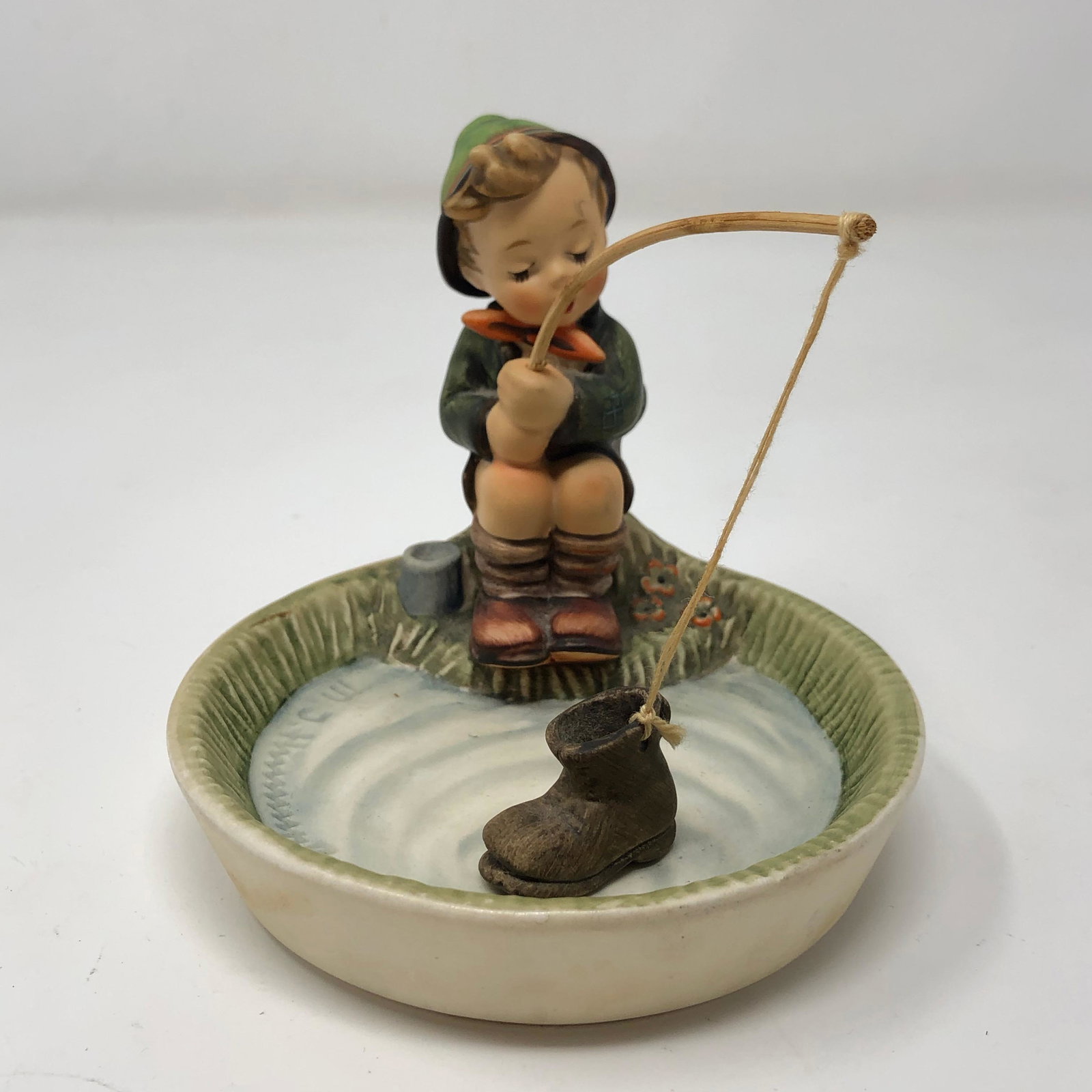 Hummel 373 'Just Fishing' TMK 6 1965: Description: Hummel 373 'Just Fishing' TMK 6 1965. Measurements: 5 H * 4.5 W * 3.5 D. Material: Porcelain, Twine.