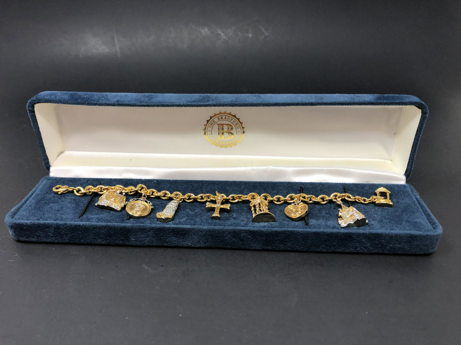 7" Golden Chain Charm Bracelet in Box: Description: 7" Golden Chain Charm Bracelet in Box. Approximate measurements: 7 inches. 8.5 x 2 inches box. Materials: goldtoned metal, fabric, board. This item has a reserve price.