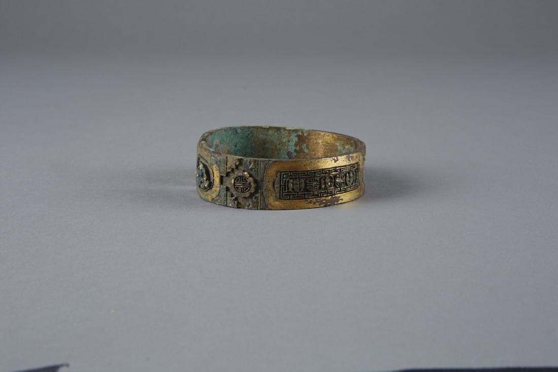 Chinese archaic Gilded Bronze Bangle pre-Ming: There are several beautiful designs and characters cast into the bangle which mirror one another on either side of the central piece. One piece has come off and is raised from the base of the bangle.