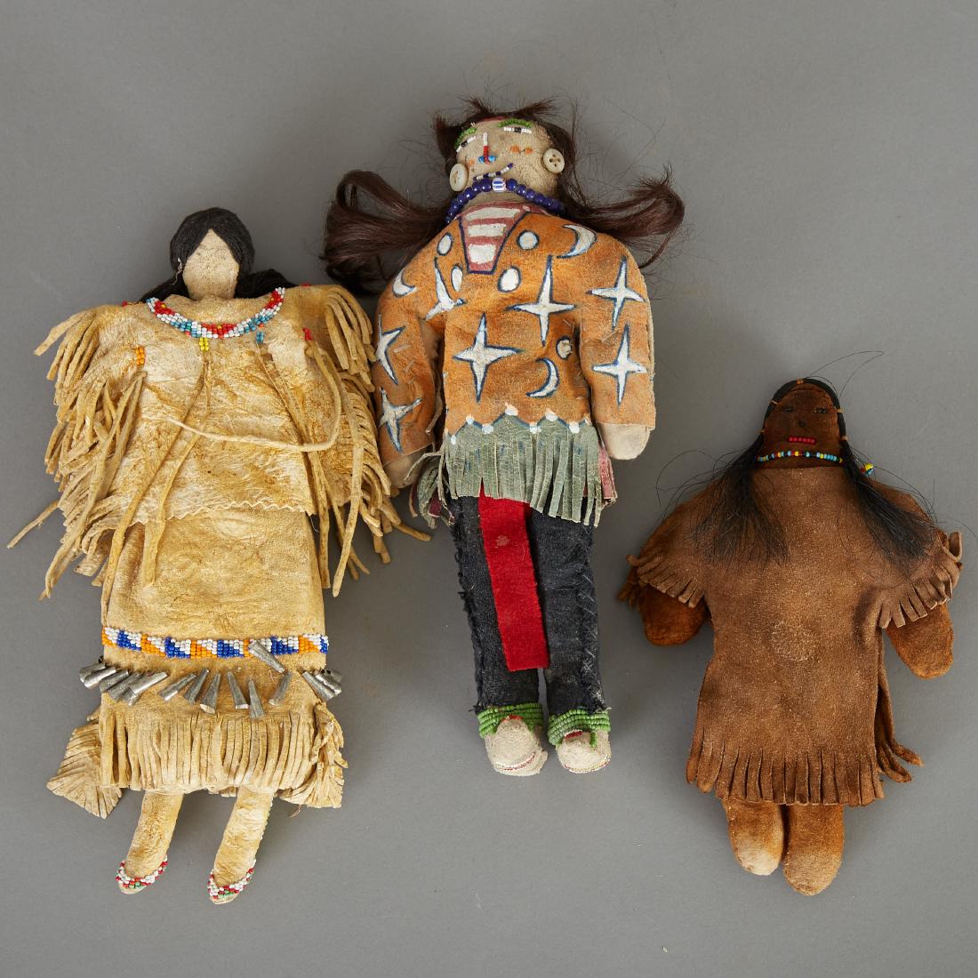 Group of 3 Native American Dolls Cheyenne Sioux Ghost: Group of three Native American dolls. One Cheyenne doll with a cloth body and hide head, poncho, and skirt. Thread hair, beaded details, and tin cones on skirt, circa early 20th century. One Sioux dol