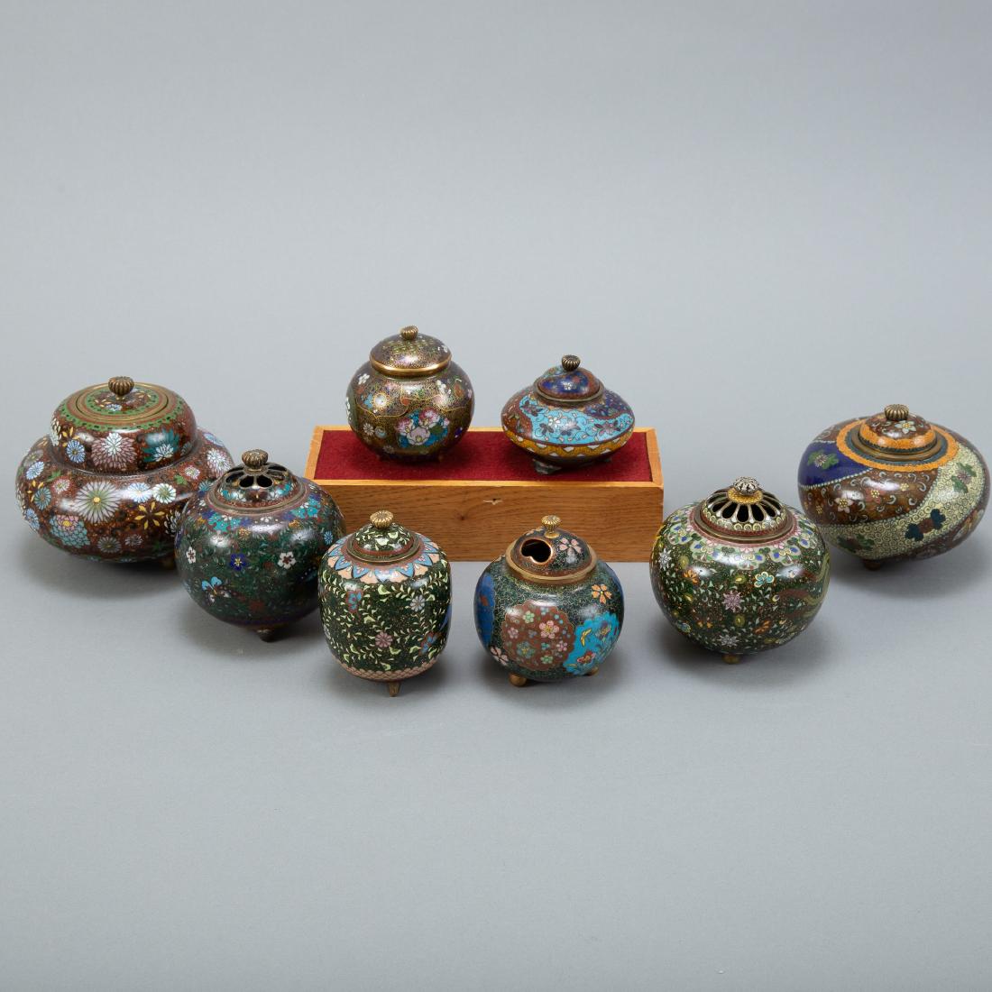 Grp: 8 Japanese Meiji Cloisonne Censers: A lovely lot of unsigned but well made Japanese Meiji period cloisonne tripod containers. Many seem to be from the same maker or workshop. Wooden stand not included. Dimensions: Height ranges from: 2 