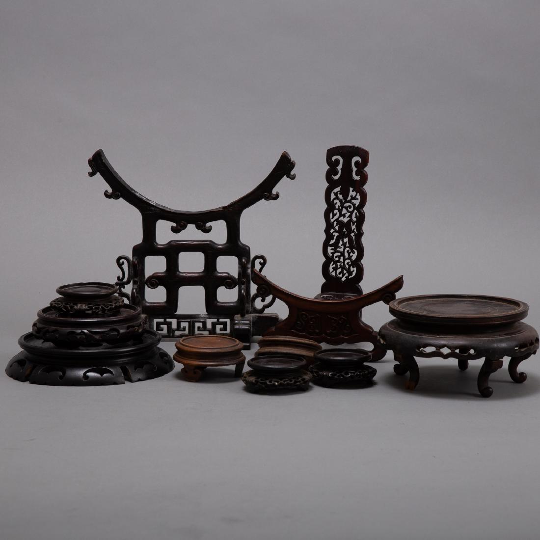 Grp Chinese Wooden Vase Stands and Tray: A large mix of Chinese stands, comprised of eleven carved wooden stands and one tray, which features a fine embroidered panel. Dimensions: Heights range from 9 3/4 in to 1 in. Diameters range from 7 3