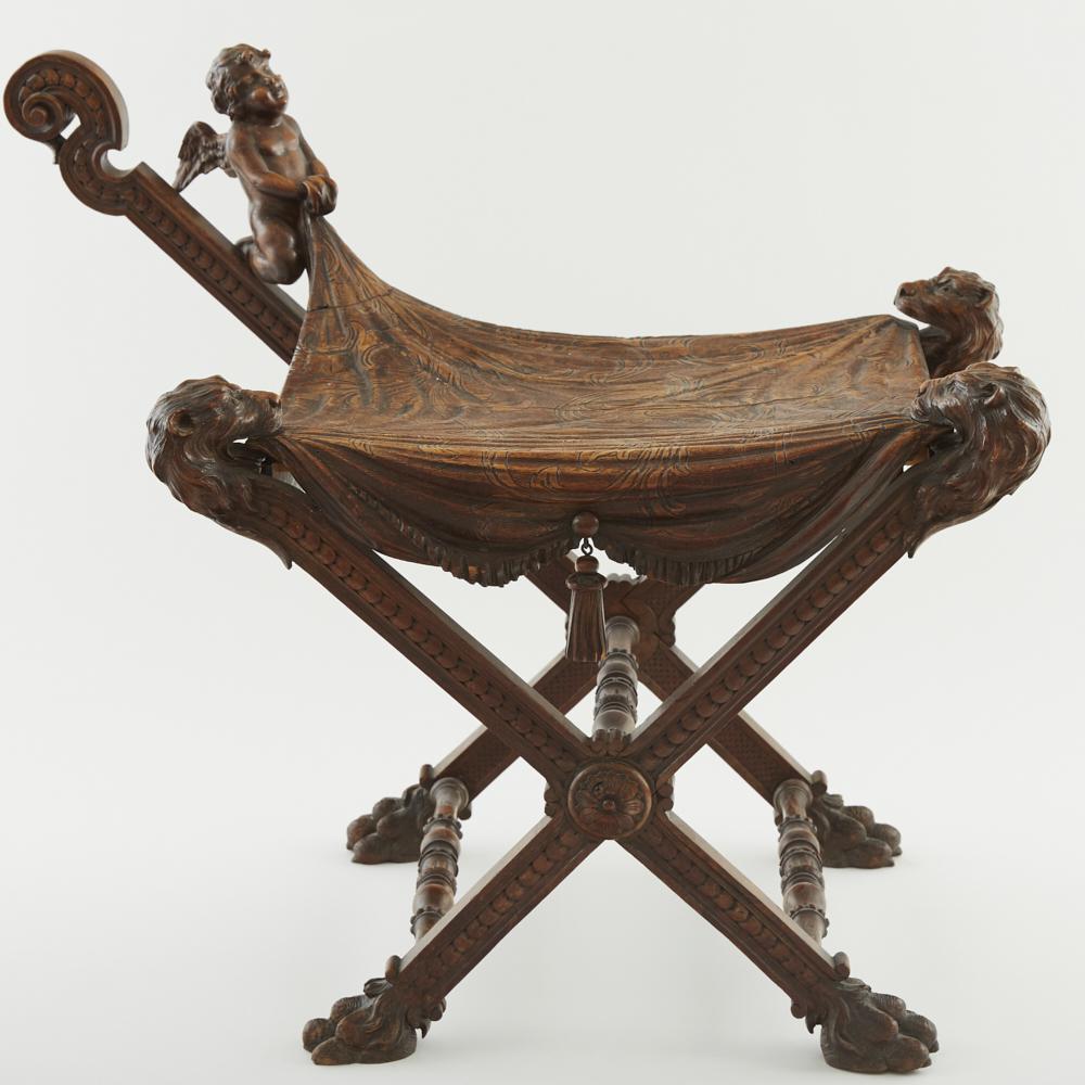 Victorian Carved Wood Bench: A Victorian tour de force of a carved wood bench or stool with lions and a cherub. The legs are capped by decorative lion feet, and the seat is carved to look like fabric. Overall a rare and excellent