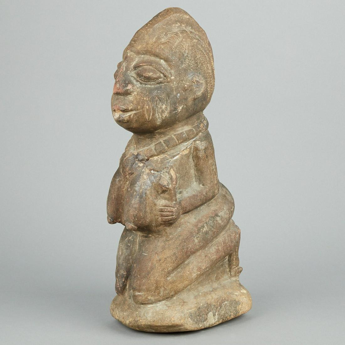 African Yoruba Kneeling Stone Figure: Yoruba stone figure depicting a kneeling woman Nigeria or Benin. This carving depicts the woman's hairstyle and face including scarification in wonderful detail. Height: 21 in x width: 7 in x depth: 1