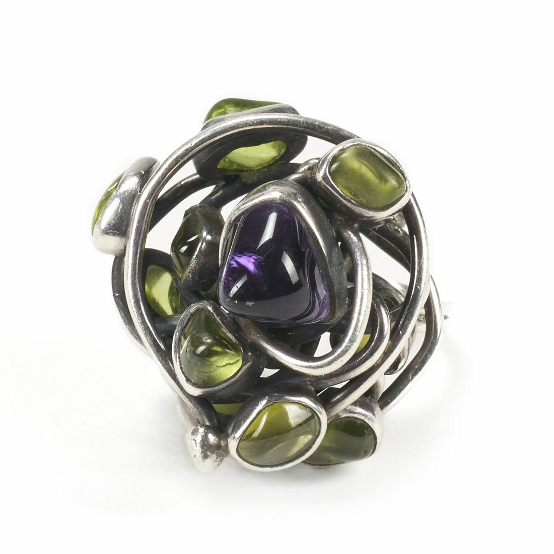 H. Fred Skaggs Silver Peridot Amethyst Ring: H. Fred Skaggs (American, 1956-1983). One mid-twentieth century Modernist inspired silver ring with a 2 millimeter gauged wire wrapped design holding bezel set tumbled peridot and amethyst. There are 