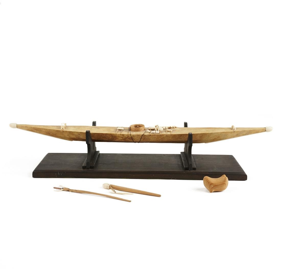 Inuit or Yup'ik Kayak w/ Tools & Seal: Inuit or Yup'ik Native American carved wooden toy kayak wrapped in seal skin with carved fishing tools and wooden seal. With wooden display stand. Keywords: Eskimo, Indian. (Without Stand) Height: 1 1