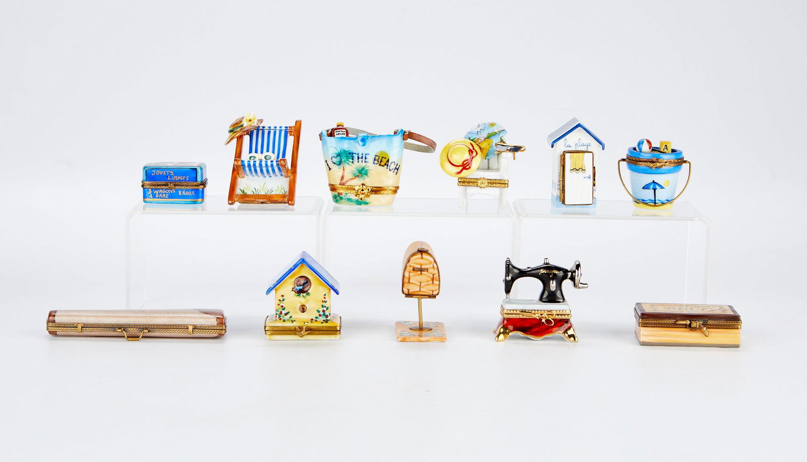 Grp: 11 French Limoges Porcelain Boxes: Limoges, France. Group of eleven assorted hand painted porcelain pill boxes including: one gun case with a small porcelain gun, two beach chairs, one mail box with two small piece of mail, one beach c