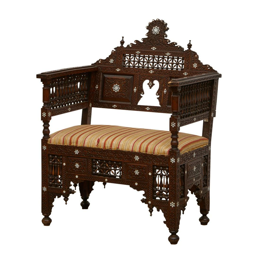 Syrian Mother of Pearl Inlaid Armchair: Syrian mother of pearl inlaid wooden armchair. The intricately carved wood is inlaid with geometric stars in mother of pearl with the intarsia method. The chair is paneled throughout with mashrabiya s