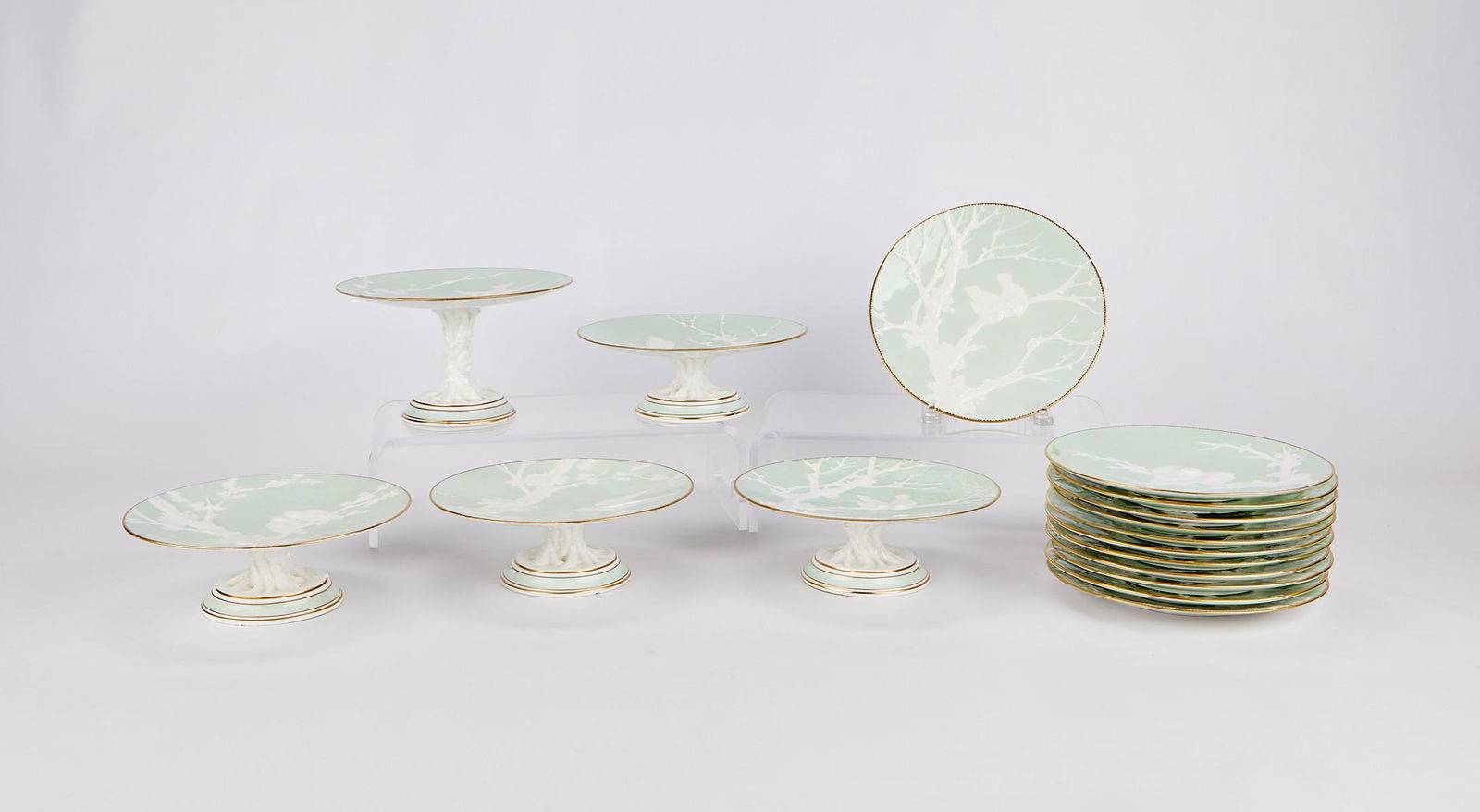 EJD Bodley Celadon Relief Molded Porcelain Dishes: E.J.D. Bodley, England. Set of celadon-ground relief-molded porcelain dishes including 12 plates, one high tazza, and four low tazzas. Impressed along the underside with a registry diamond for 29 Janu