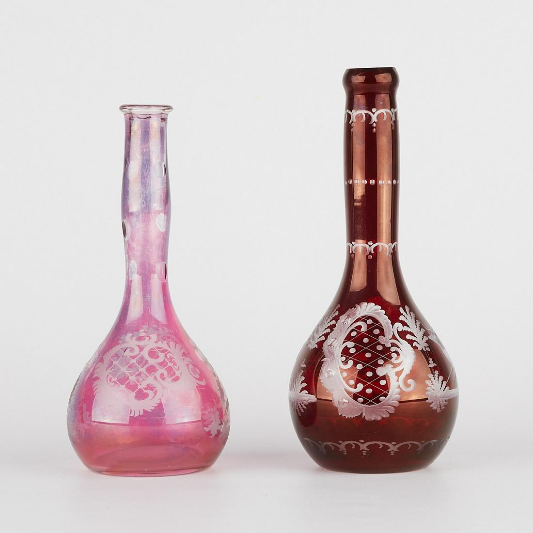 Pair of Red Glass Barber Bottles w/ Deer: Pair of antique hand-blown glass barber bottles, both decorated with deer and a house. One in a deep red with cut glass decoration; the other in a lighter red or cranberry-red with etched decoration. 