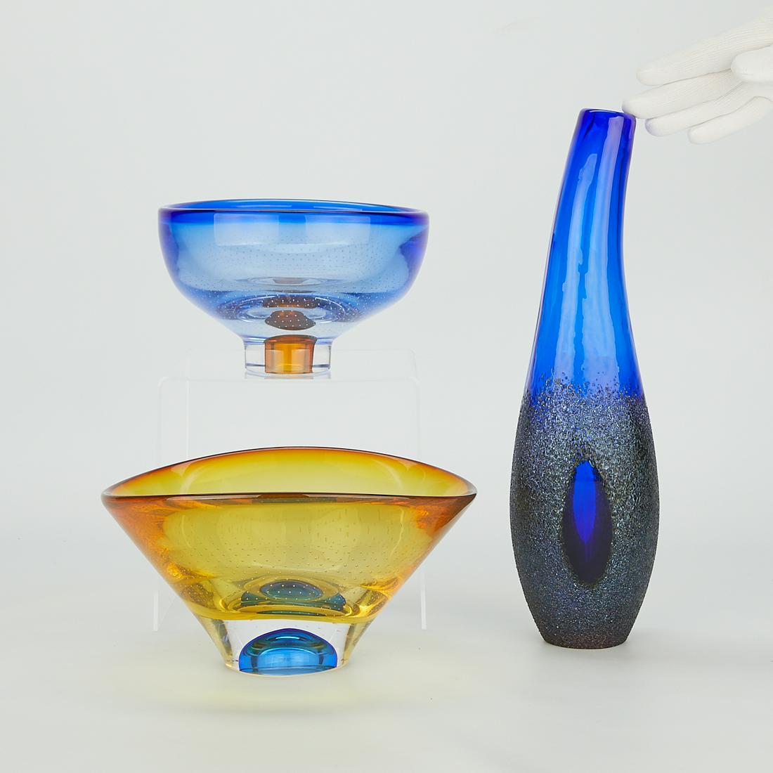 Group of 3 Kosta Boda Swedish Glass Vessels: Kosta Boda, Sweden. Group of three art glass vessels, all signed and numbered along the underside. Two bowls by Goran Warff (Swedish, 1933-2022). Both in yellow and blue with uniform bubble inclusions
