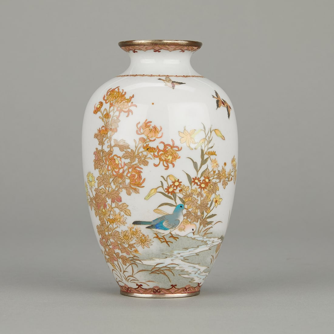 Japanese Cloisonne Bird Vase Style of Kodenji: One Japanese cloisonne vase. Elaborately decorated with blooming flowers and birds against a pale blue ground. In the style of Hayashi Kodenji.Height: 6 in x diameter: 3 1/2 in.