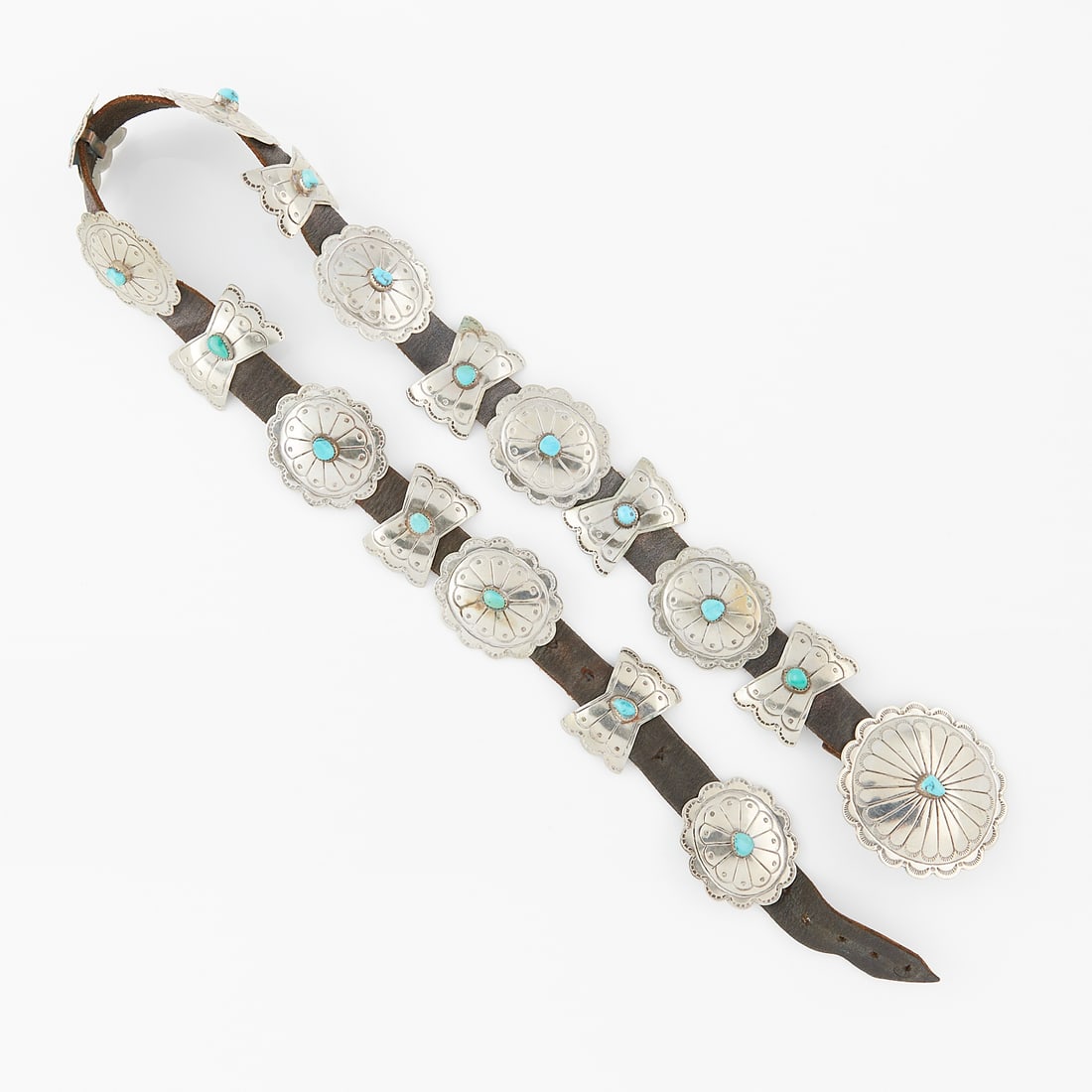 Silver Concho Belt w/ Turquoise: Silver concho belt with set with turquoise. Central buckle of oval form with stamped design set with one turquoise. The remaining 16 placards are alternating of oval form and X form each with stamped 