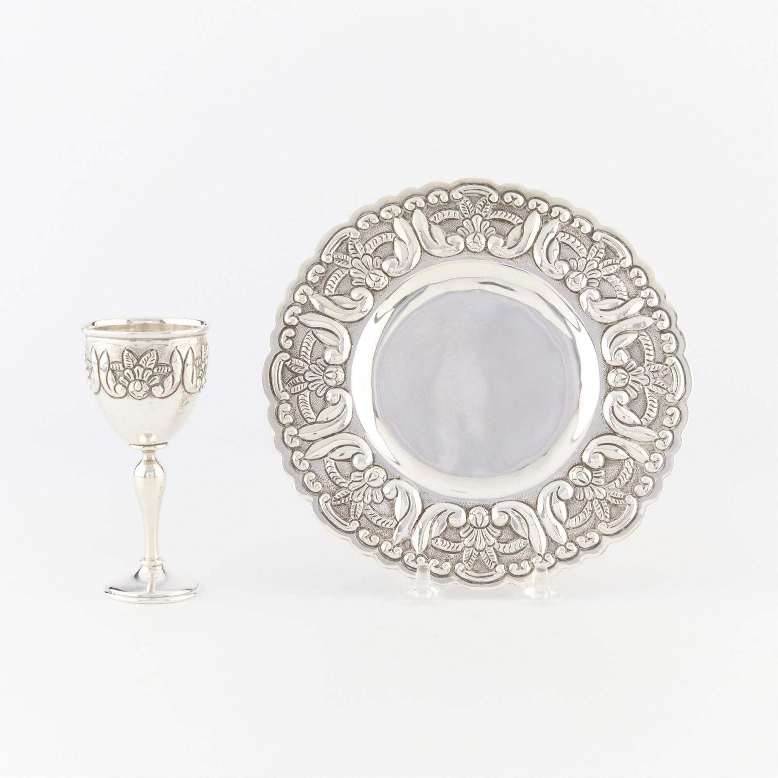 Sterling Wine Coaster & Chalice 9.82 ozt: Wine coaster and small tasting chalice. Both with repousse floral design. Each marked with maker's mark of a shield shaped cartouche and knight on horseback, sterling 925, and 14064 and 14653.(Plate)