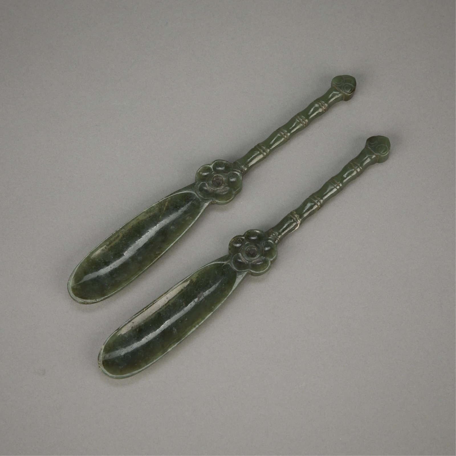 2 Chinese Carved Jade Netsuke Tea Spoons: Pair of Chinese carved jade netsuke spoons or tea scoops. Each spoon is of a rich and verdant spinach green jade with a flower skillfully carved along the neck, where the stem meets the bowl of the sp
