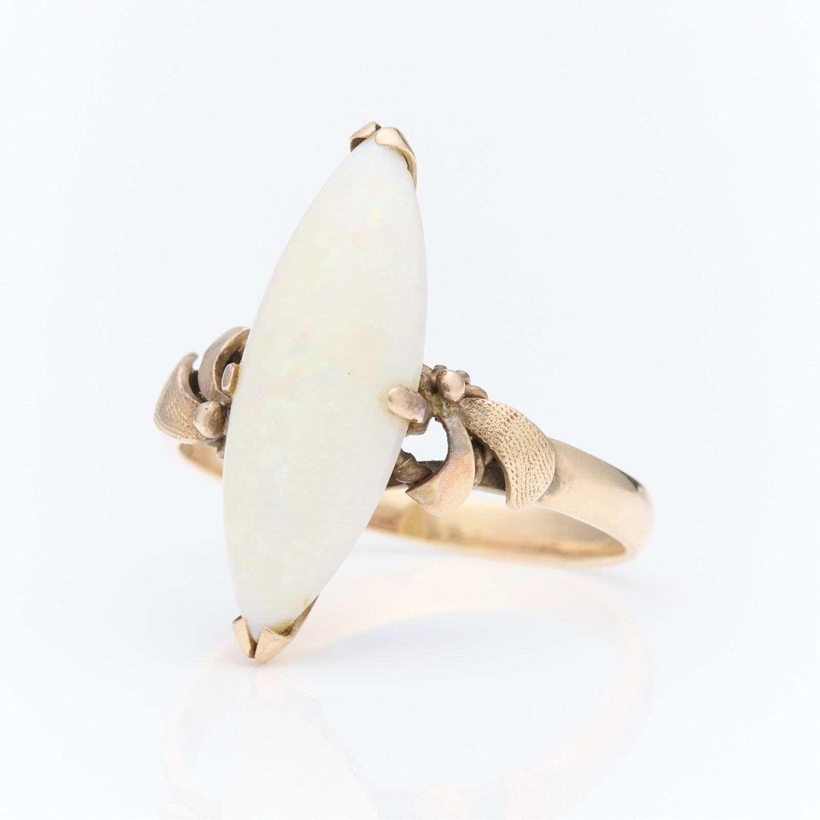 14k Yellow Gold Opal Navette Ring: 14k yellow gold ring set with central navette form white opal. The shoulders of the ring accented with textured and curling ribbons. The gallery of the ring with decorative pierced filigree. Marked 14